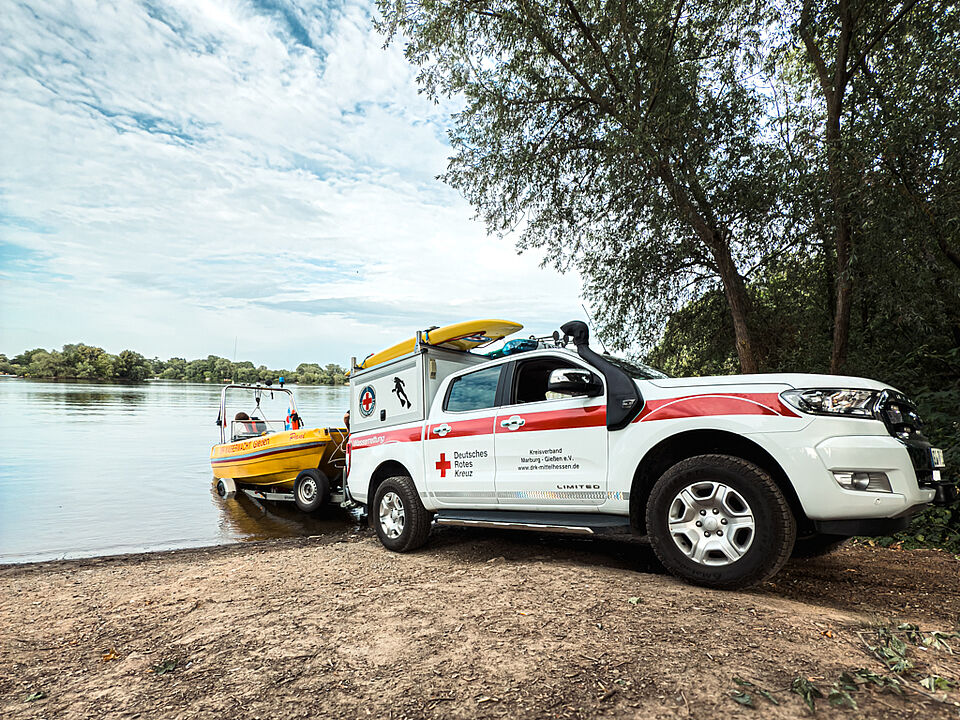 DRK Wasserwacht Mittelhessen – Einsatzfahrzeug mit Rettungsboot am See Einsatzfahrzeug der DRK Wasserwacht zieht gelbes Rettungsboot ins Wasser
