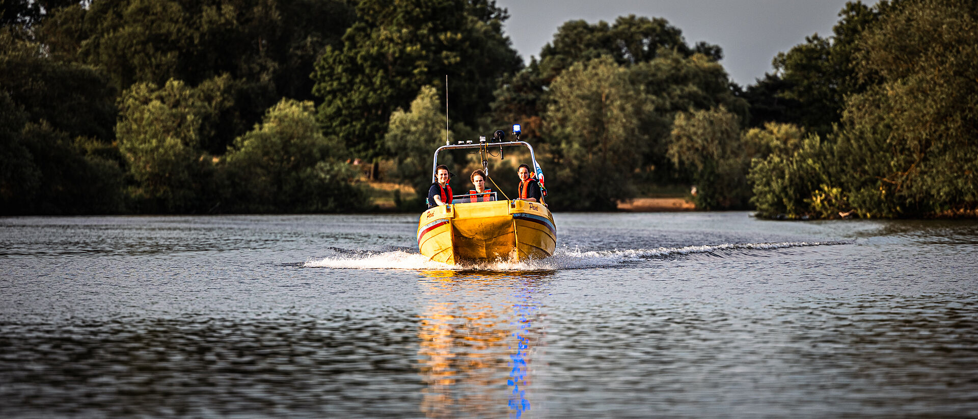 DRK Wasserwacht Mittelhessen – Ehrenamt im Einsatz auf dem See Mitglieder der DRK Wasserwacht auf einem gelben Rettungsboot bei einer Übung auf dem See