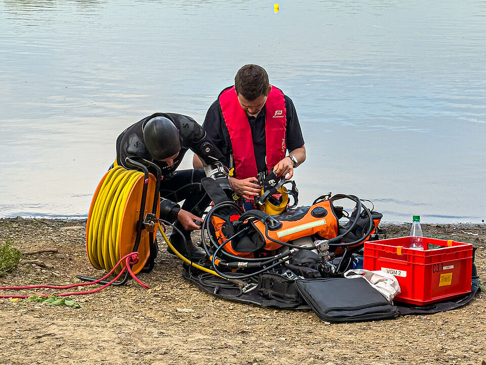 DRK Wasserwacht Mittelhessen – Ausrüstung für Tauch-Einsatz Zwei Mitglieder der DRK Wasserwacht prüfen Tauch- und Atemausrüstung am Ufer