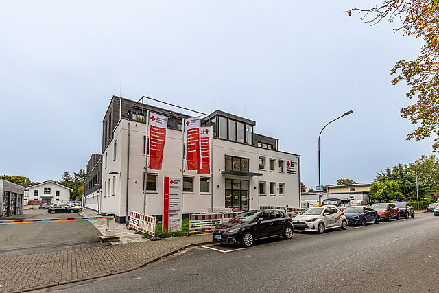 DRK Kreisverband Marburg-Gießen – Verwaltungs- und Kursstandort in der Eichgärtenallee Gebäude des DRK Kreisverbands Marburg-Gießen in der Eichgärtenallee mit DRK-Fahnen und geparkten Einsatzfahrzeugen