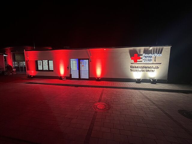 DRK Kursstandort Wetter – Schulungszentrum für Erste Hilfe und Katastrophenschutz DRK-Stützpunkt Wetter bei Nacht mit rot beleuchtetem Gebäude und DRK-Logo
