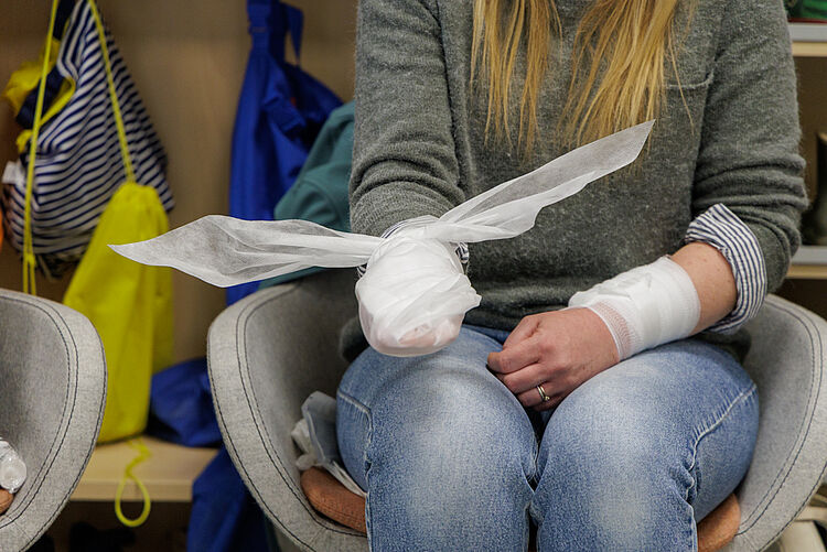 Erste Hilfe am Kind – Verband am Arm anlegen Teilnehmerin mit verbundenem Arm übt Verbandtechnik im Erste Hilfe Kurs für Kinder