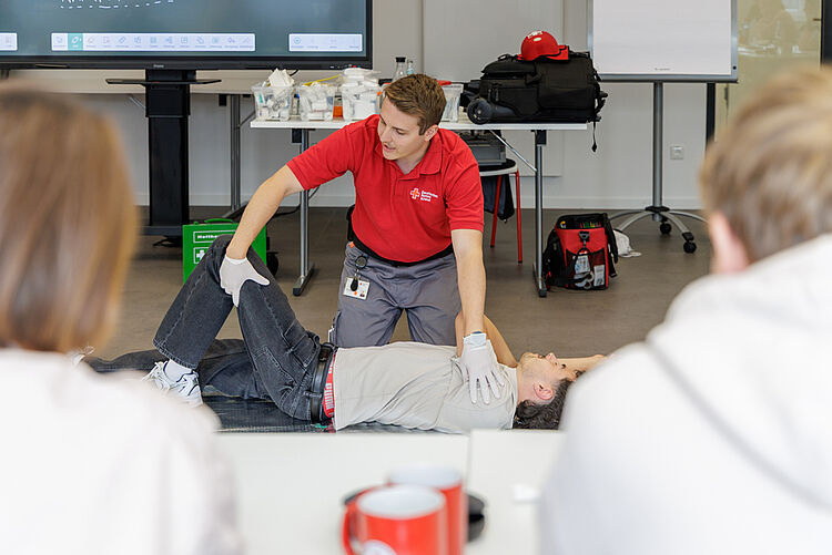 DRK Erste-Hilfe-Kurs: stabile Seitenlage üben DRK-Ausbilder zeigt Teilnehmenden die stabile Seitenlage in einem Erste-Hilfe-Kurs