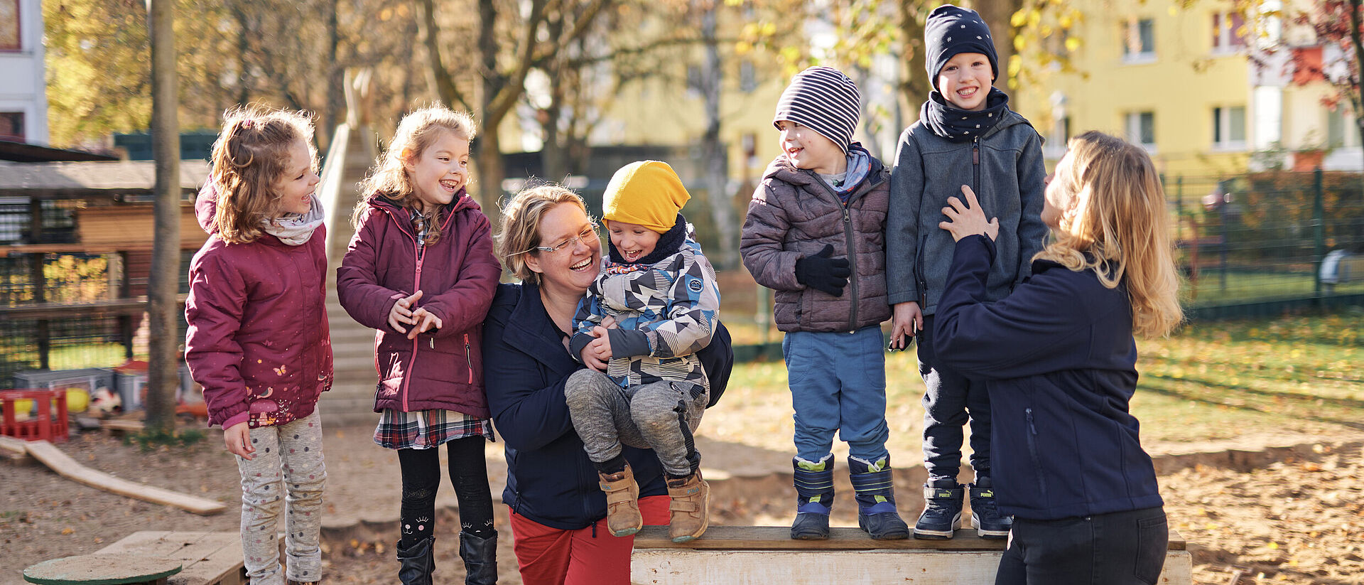Gemeinsam stark – Kinder und Erzieherinnen in der DRK-Kita Mittelhessen Kinder und Erzieherinnen lachen gemeinsam auf dem Spielplatz einer DRK-Kita