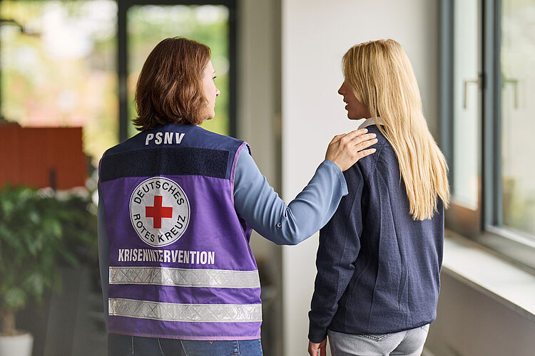 DRK Mittelhessen – Psychosoziale Notfallversorgung bietet Beistand und Unterstützung PSNV-Helferin des DRK legt einer Person tröstend die Hand auf die Schulter