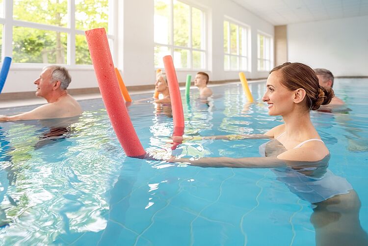 Aquafitness beim DRK Mittelhessen – Gesund und gelenkschonend trainieren Gruppe von Menschen macht Aquafitness mit bunten Poolnudeln im Schwimmbad