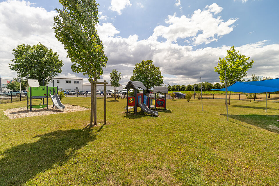 Außengelände der DRK-Kita „Henrys Märchenwelt“ in Heuchelheim Spielplatz mit Rutsche, Häuschen und Sonnenschutz im Garten der DRK-Kita Heuchelheim