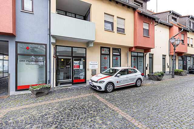 DRK Physiotherapiepraxis in Laubach – Gesundheitsversorgung vom Roten Kreuz Eingang der DRK Physiotherapiepraxis Mittelhessen in Laubach mit DRK-Fahrzeug vor dem Gebäude