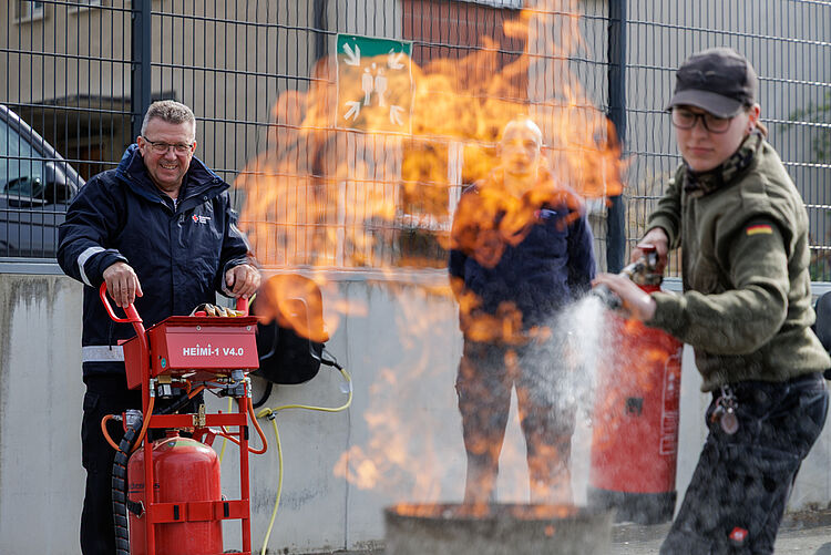 Brandschutzhelfer Ausbildung Praxis DRK Mittelhessen Teilnehmer löscht Brandherd mit Feuerlöscher unter Anleitung eines Ausbilders