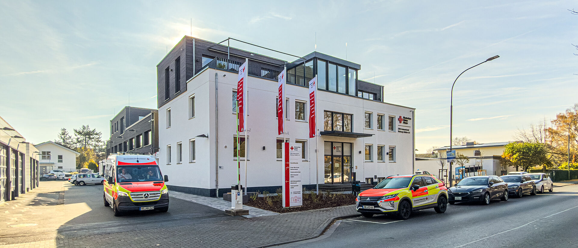 DRK Kreisverband Marburg-Gießen – Verwaltungs- und Kursstandort in der Eichgärtenallee Gebäude des DRK Kreisverbands Marburg-Gießen in der Eichgärtenallee mit DRK-Fahnen und geparkten Einsatzfahrzeugen