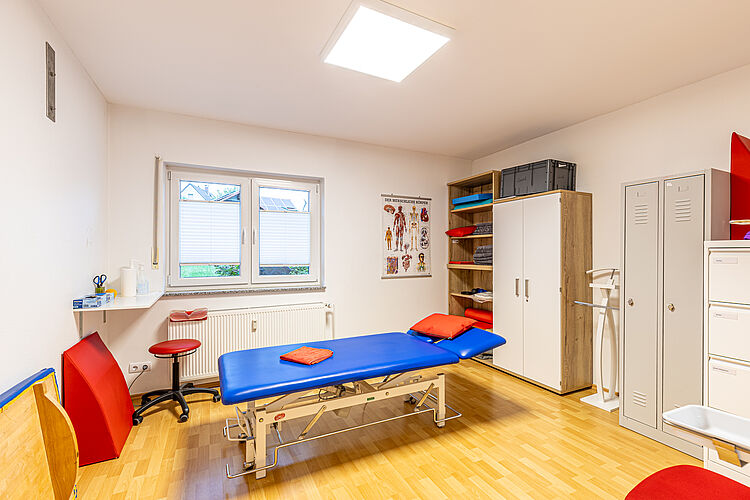 Behandlungsraum mit blauer Liege – DRK Therapiepraxis Alten-Buseck Behandlungsraum mit blauer Therapieliege und Anatomieposter