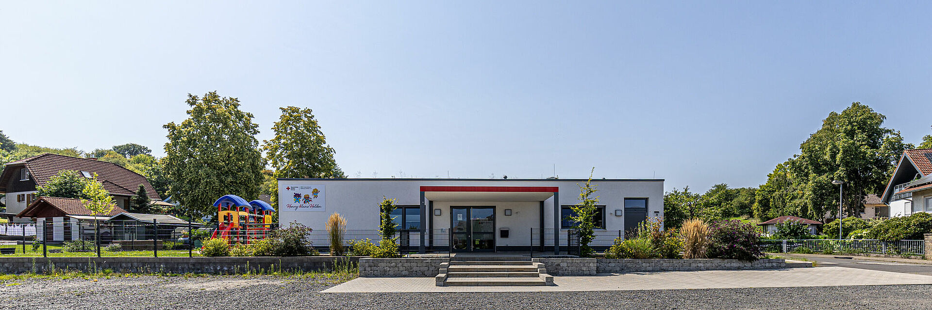 DRK-Kita Henrys kleine Helden in Rabenau-Geilshausen – moderne Kindertagesstätte mit Herz Außenansicht der DRK-Kita Henrys kleine Helden in Rabenau-Geilshausen mit Spielplatz und Garten