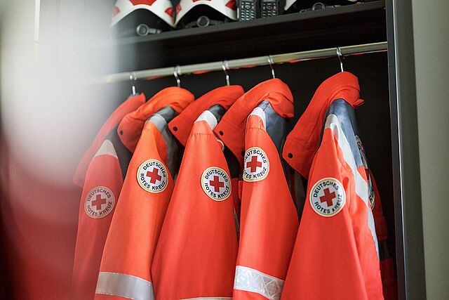 Einsatzkleidung des Deutschen Roten Kreuzes bereit zum Einsatz DRK-Jacken und Helme ordentlich in Spind aufgehängt