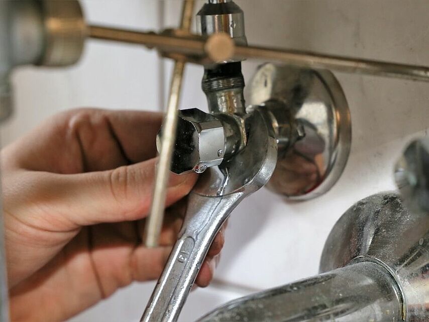 Professioneller Installationsservice – DRK Alltagshelden Mittelhessen Handwerker zieht eine Schraube an einem Ventil mit einem Schraubenschlüssel fest