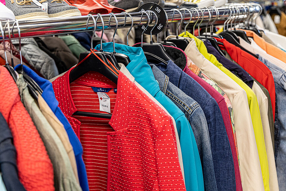 Bunte Jacken und Mäntel im DRK Kleiderladen Gießen Kleiderstange mit Jacken und Oberteilen in verschiedenen Farben
