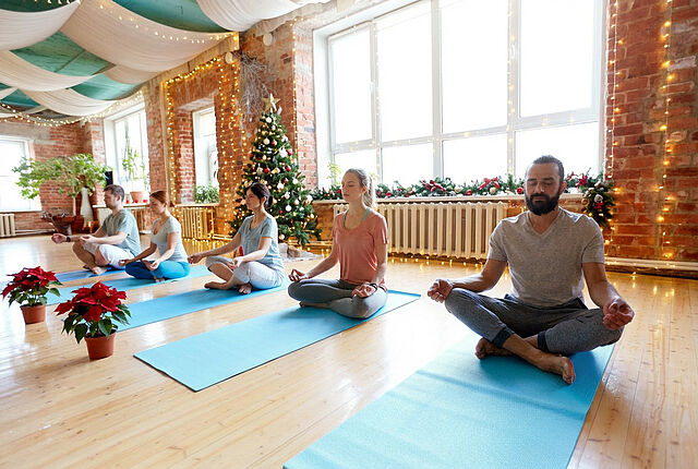 Entspannter Yoga-Kurs in der Weihnachtszeit Gruppe beim meditativem Yoga in weihnachtlich geschmücktem Raum