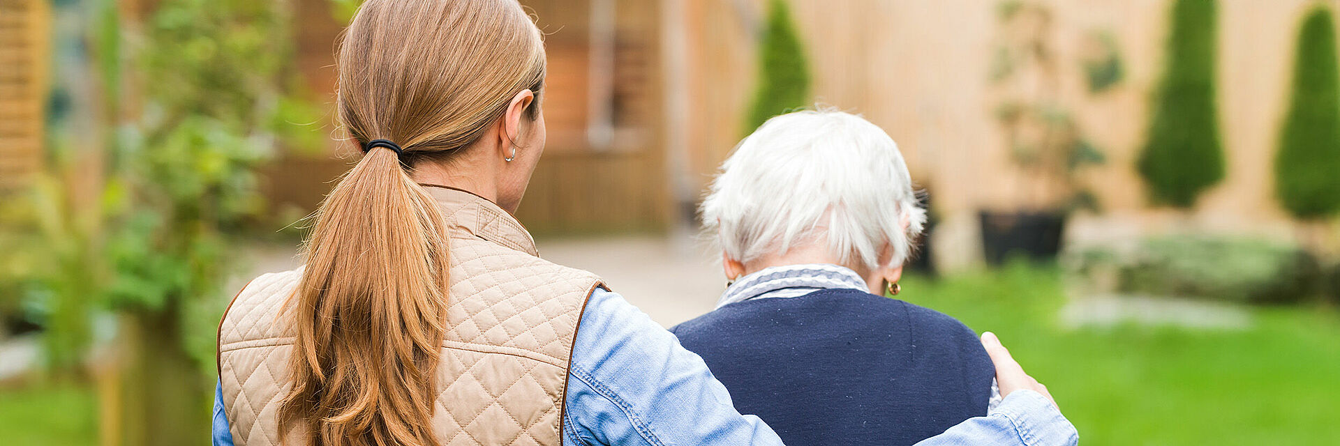 Demenzberatung Mittelhessen – Begleitung für Senioren & Angehörige Jüngere Frau unterstützt Seniorin beim Gehen im Garten