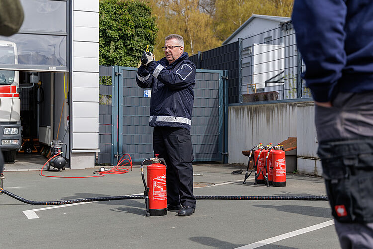 Brandschutzhelfer Training Feuerlöscher Praxis DRK Mittelhessen Ausbilder erklärt die Handhabung eines Feuerlöschers während einer praktischen Brandschutzübung