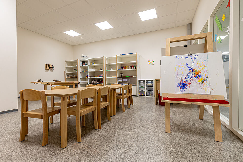Kreativraum der DRK-Kita „Henrys Märchenwelt“ in Heuchelheim Bastel- und Malraum mit Holztischen, Staffelei und Regalen voller Materialien in der DRK-Kita Heuchelheim