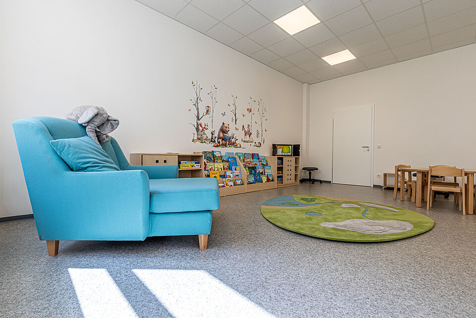 Leseecke und Gruppenraum der DRK-Kita Heuchelheim Heller Gruppenraum mit blauer Sitzlounge und Bücherregalen in der DRK-Kita „Henrys Märchenwelt“