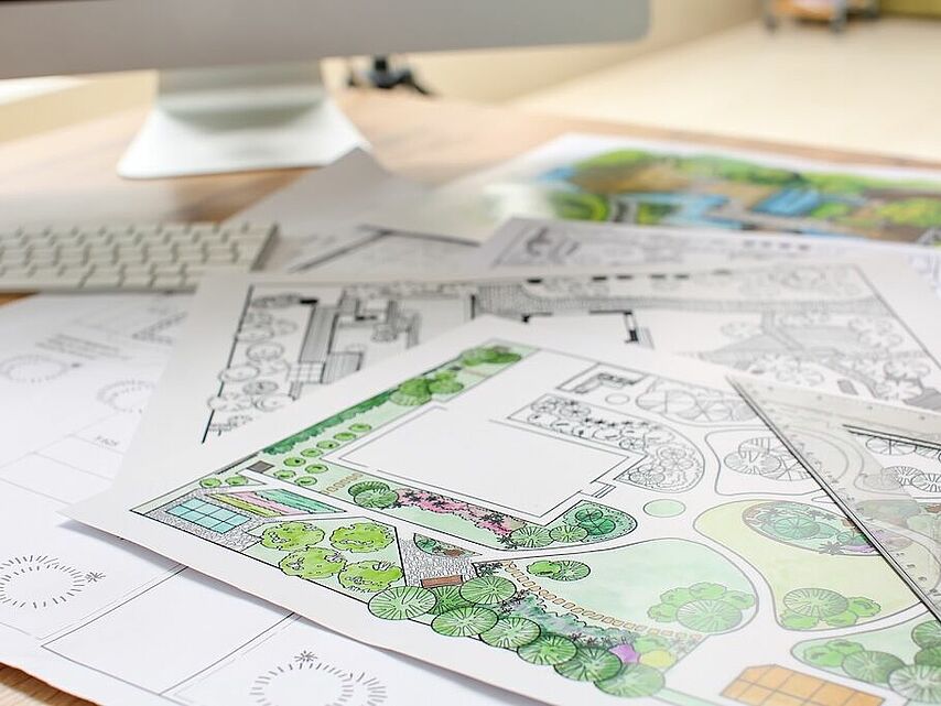 Garten- und Landschaftsplanung vom DRK Facility Service Mittelhessen Landschaftsplan mit Bepflanzungsskizze und Gartenentwurf auf einem Schreibtisch