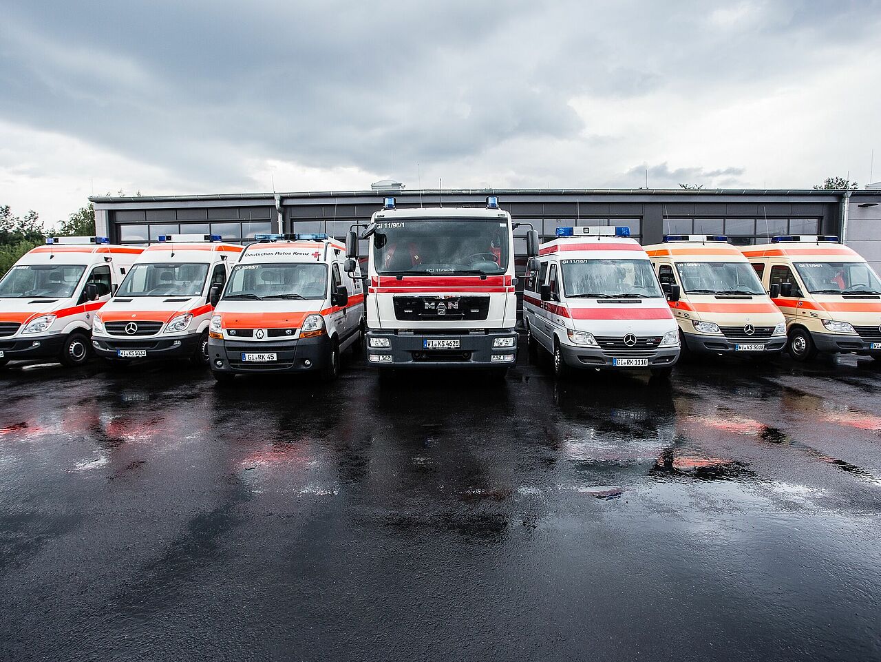 Sanitätszüge des DRK Mittelhessen – Einsatzbereit bei jeder Lage Fahrzeuge des DRK Sanitätszugs bei nasser Fahrbahn vor der Fahrzeughalle