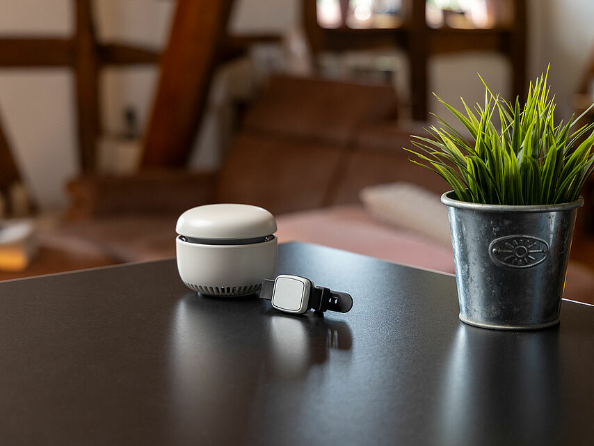 Hausnotrufgerät des DRK Mittelhessen – moderne Sicherheitstechnik Hausnotrufgerät mit Notrufarmband auf einem Tisch in gemütlicher Wohnumgebung