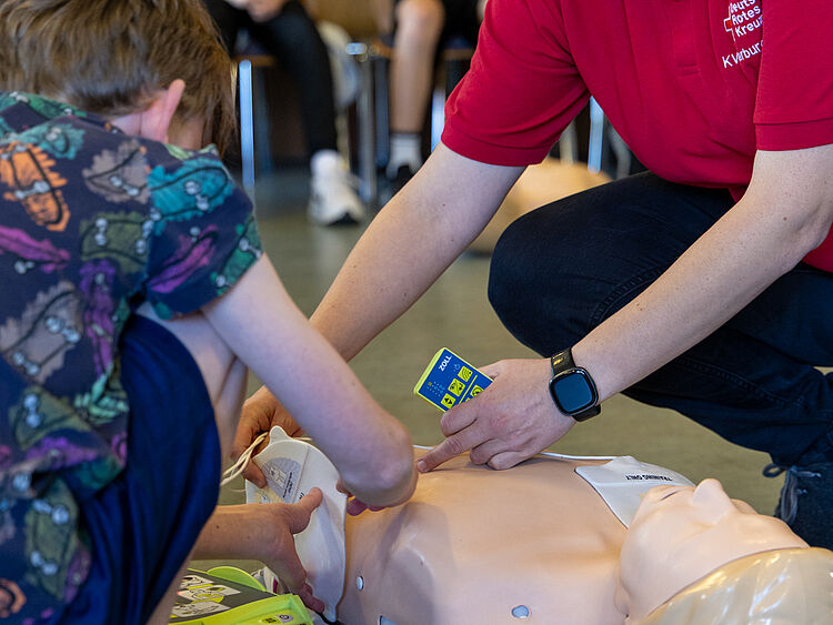 Erste-Hilfe-Training an Schule: AED-Übung mit dem DRK Schüler und DRK-Ausbilder trainieren den Einsatz eines AED-Geräts an Reanimationspuppe