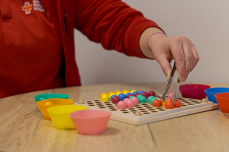 Ergotherapie Feinmotorik Übungen Ergotherapeutische Feinmotorikübung mit bunten Kugeln und Pinzette